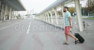 穿着t恤、短裤和耳机的年轻英俊的非洲游客正在往机场走的时候<strong>拉</strong>着<strong>行李</strong>